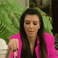 a woman in a pink jacket is holding a piece of food in her hand .