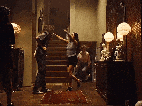 a group of people are dancing in a hallway with stairs .