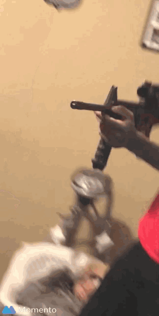 a person is holding a gun in front of a wall with the word momento on the bottom right