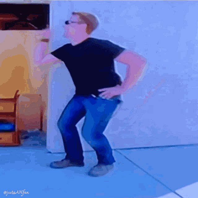 a man in a black shirt and blue jeans is dancing on a blue floor