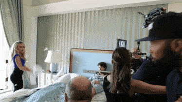 a man in a hospital gown is laying on a bed with a woman in a blue dress standing behind him