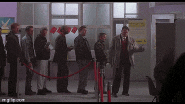 a group of men are standing in a line behind a red rope and a sign that says " moving & storage "