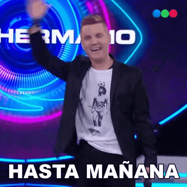 a man in a suit stands in front of a sign that says hermano hasta manana