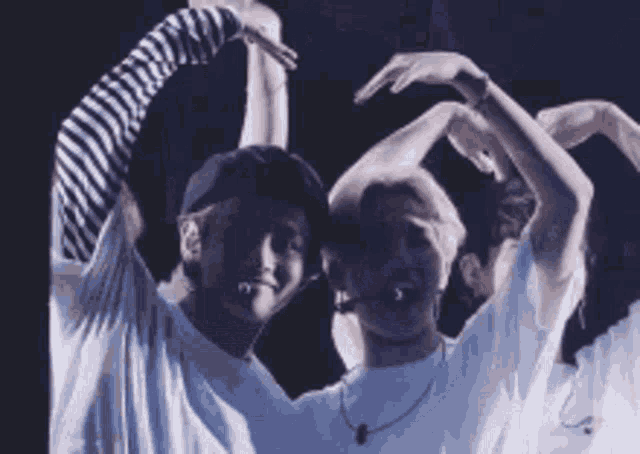 a group of people are making a heart shape with their arms .