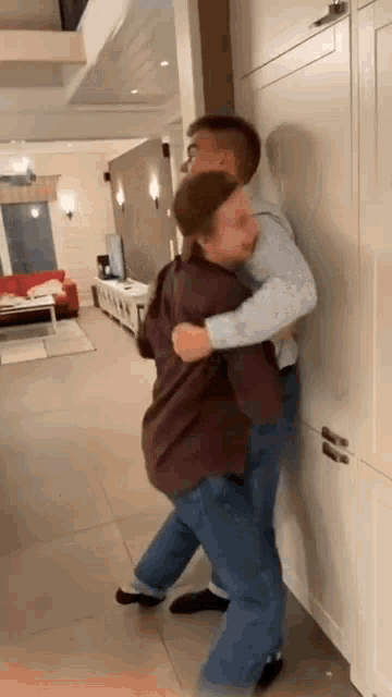 a man is carrying a woman in his arms while standing against a wall .