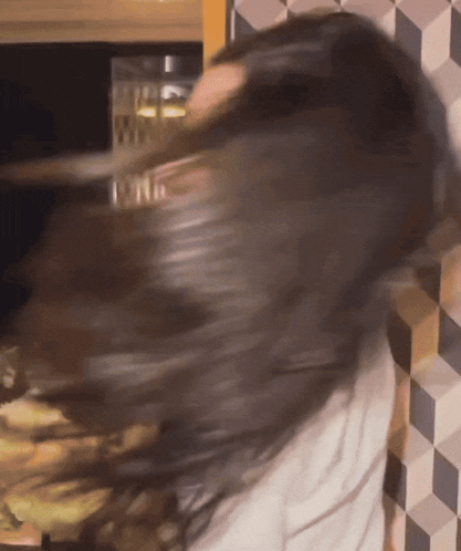 a woman 's hair is blowing in the wind in front of a tiled wall