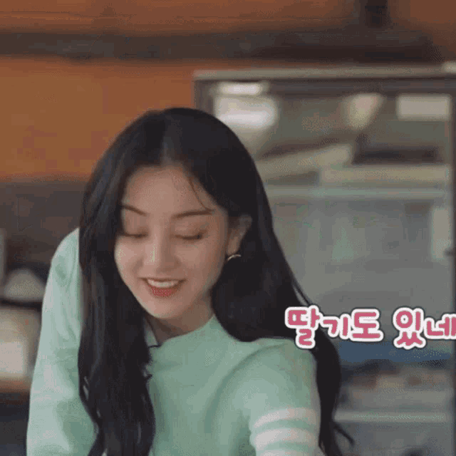 a woman in a green sweater is smiling in front of a display case .