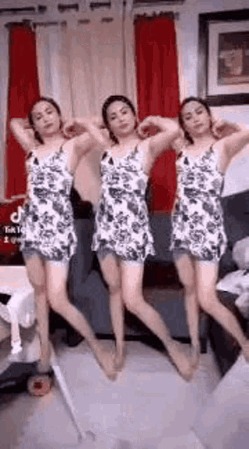 a woman is dancing in a living room with three different dresses on .