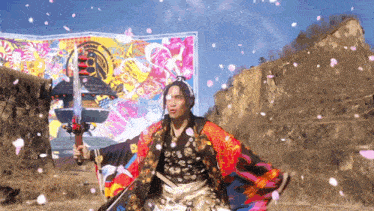 a man in a colorful costume holds a sword in front of a colorful wall