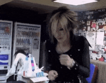 a woman in a black jacket is standing in front of a pocari sweat machine .