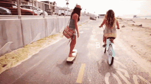 a woman riding a bike and another woman riding a skateboard