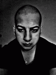 a man with a shaved head is wearing a black shirt and necklace