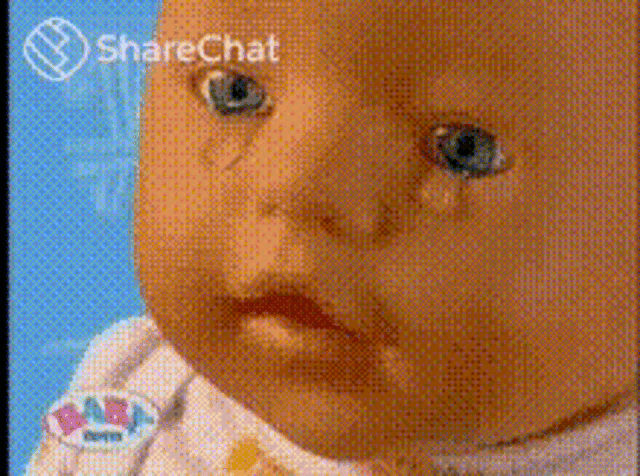 a close up of a baby doll 's face with a sharechat logo in the background