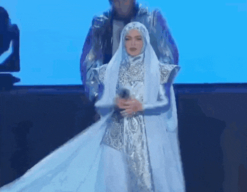 a woman in a white dress is holding a microphone while standing next to a man .