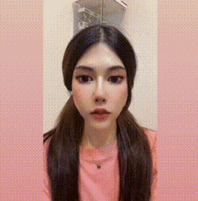 a woman with long hair and pigtails is wearing a pink shirt and necklace .