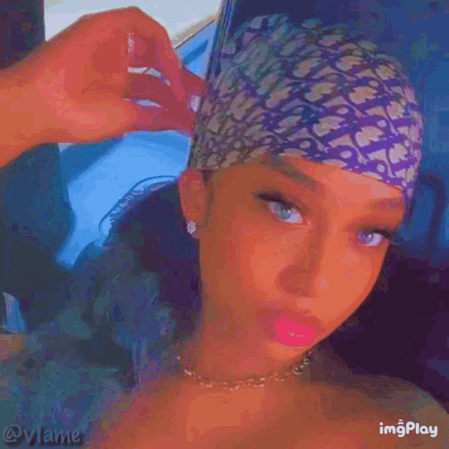 a woman wearing a headband and a necklace is taking a selfie .