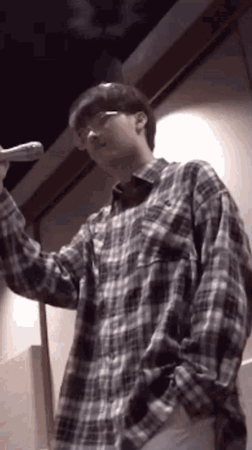 a man in a plaid shirt is holding a microphone in his hand