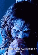 a close up of a person with a scary face covering their mouth with their hands .