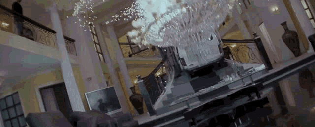 a car is driving down a set of stairs in a large room with a chandelier .