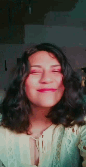 a woman with curly hair is making a face with her eyes closed
