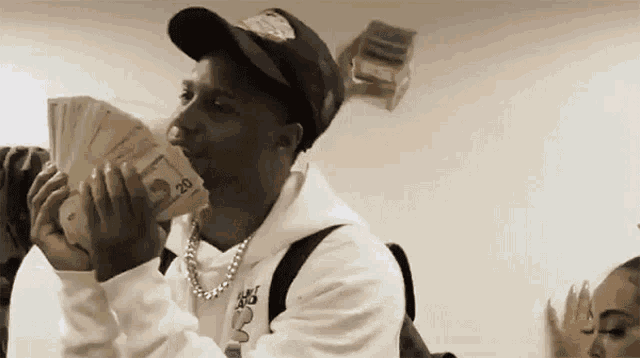 a man is holding a bunch of money in his mouth while another man throws money in the air .