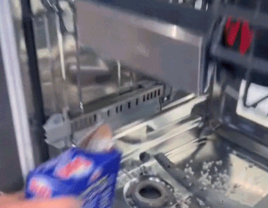 a person is cleaning a dishwasher with a bag of soap .