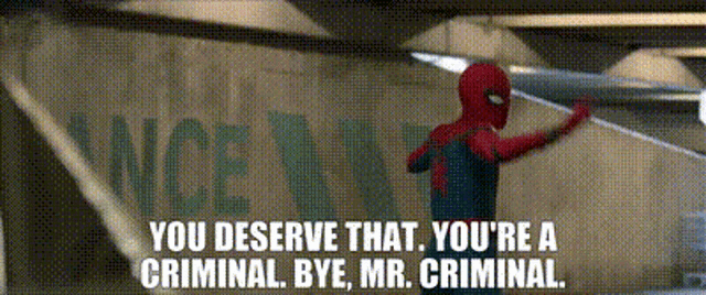 a man in a spiderman costume is standing in front of a sign that says you deserve that you 're a criminal