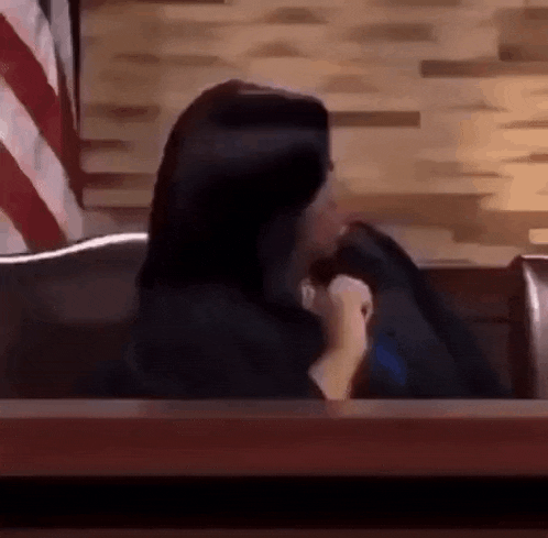 a woman is sitting in a judge 's chair in a courtroom .