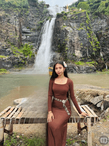 a woman sitting on a bench in front of a waterfall