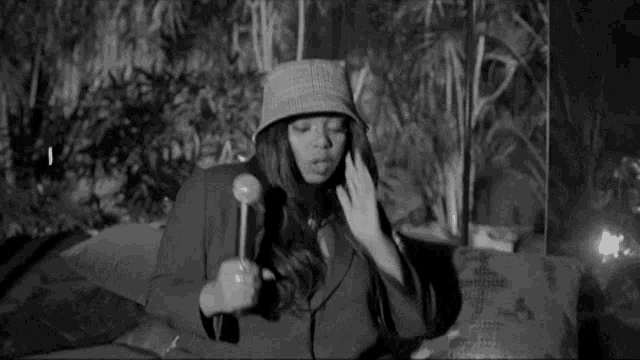 a black and white photo of a woman wearing a hat and jacket .