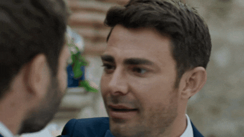 a man in a suit is talking to another man in a white shirt