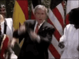 a man in a suit and tie is dancing in front of a group of people