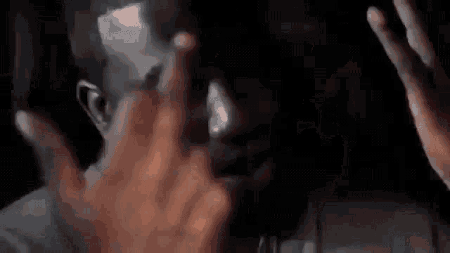 a close up of a man covering his face with his hand .