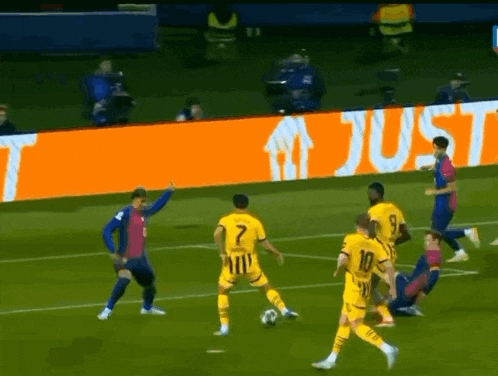 a group of soccer players on a field with an orange sign that says just in the background