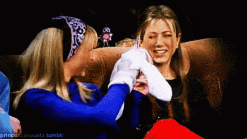 two women are sitting next to each other on a couch holding hands and smiling .