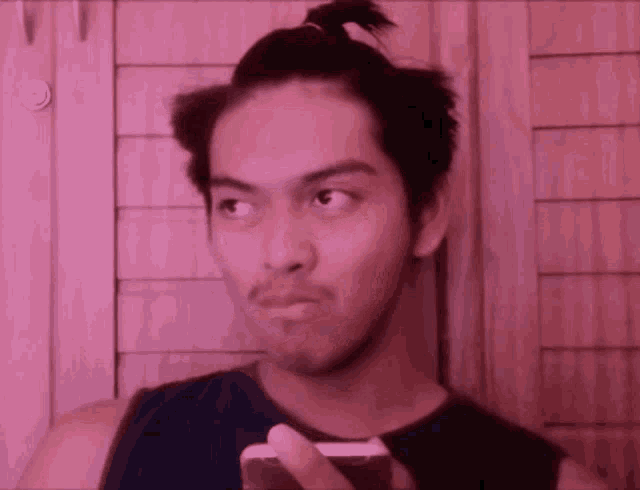 a man with a bun on his head holds a cell phone
