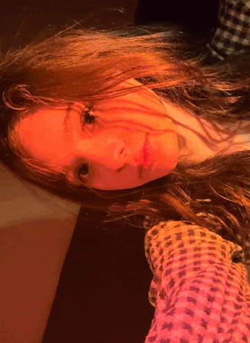 a close up of a woman 's face with a plaid shirt