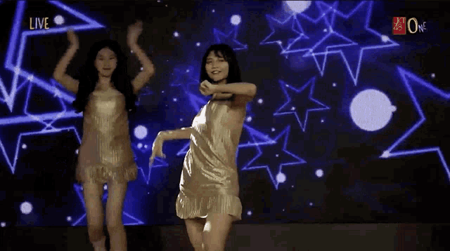 two women are dancing in front of a live screen