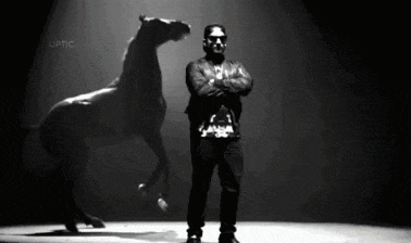 a man with his arms crossed stands in front of a horse that is standing up