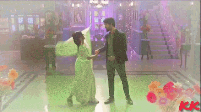 a man and a woman are dancing in a room with purple lights and the word kk on the bottom