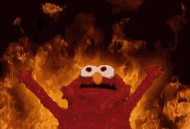 elmo from sesame street is standing in front of a fire with his arms outstretched .