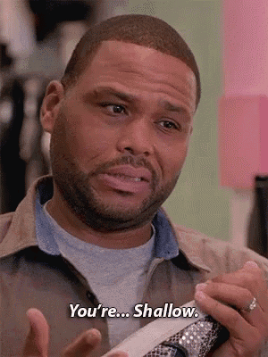 a man with a beard is holding a pair of shoes and says `` you 're ... shallow '' .