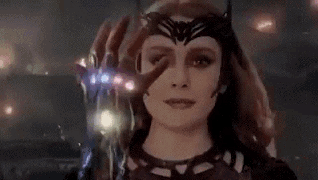 scarlet witch is holding a hand with the infinity gauntlet on it and says `` being ... '' .