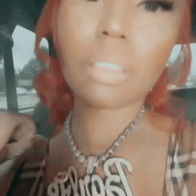 a woman with red hair is wearing a necklace with the word snoop on it