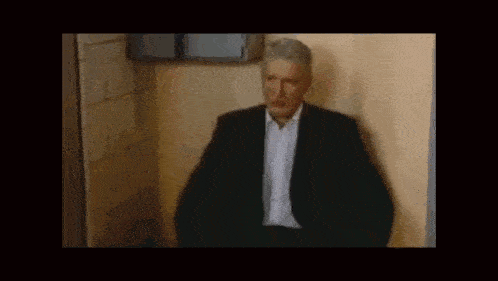 a man in a suit and tie is sitting in a bathroom .