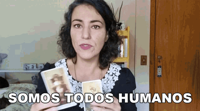 a woman holding two cards with the words somos todos humanos above her