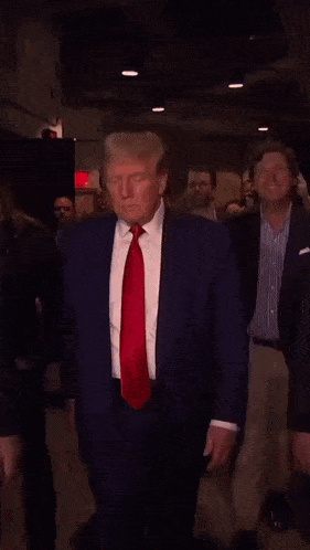 a man in a suit and red tie is walking with another man