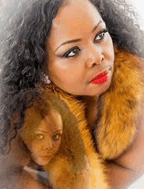 a woman wearing a fur coat and red lipstick has a reflection of herself in the fur coat .