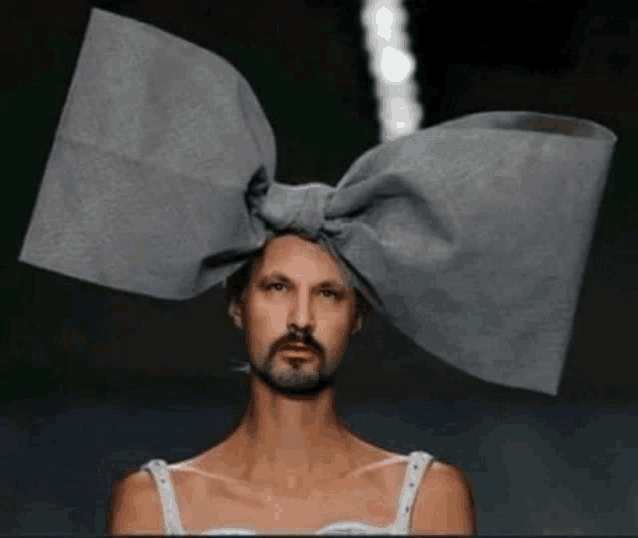 a man with a beard is wearing a gray bow on his head