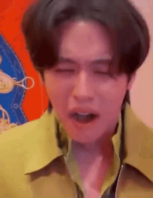 a young man in a yellow jacket is crying with his eyes closed .